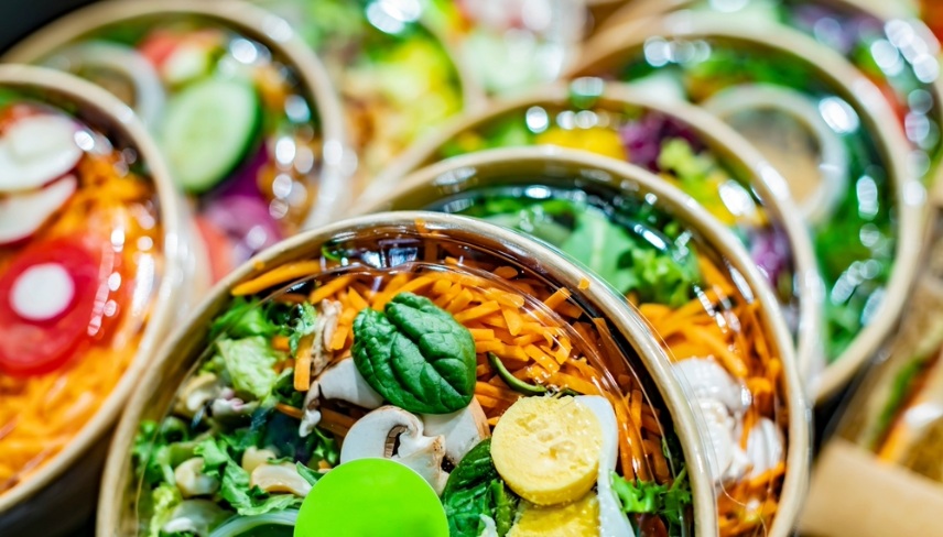 Pre-packaged vegetable salads displayed in a commercial refrigerator