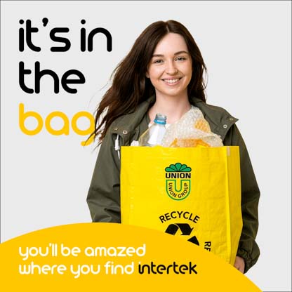 A woman smiling while carrying a bag full of recyclable content
